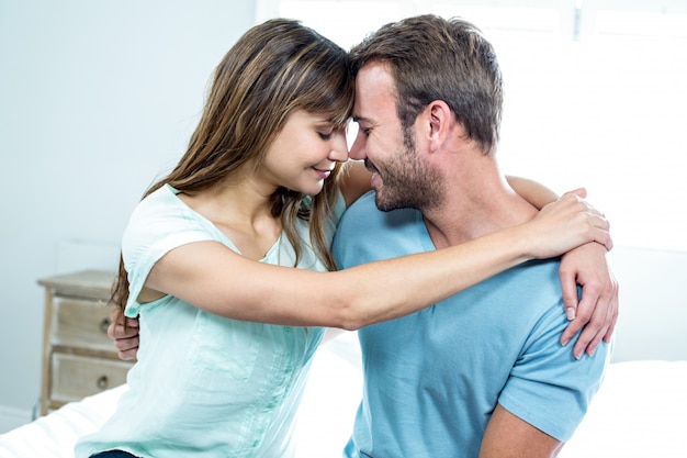 Casal feliz abraçando na cama em casa