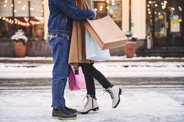 Casal feliz abraçando na rua nevada depois das compras