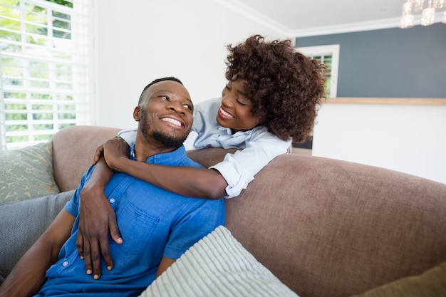 Casal feliz abraçando no sofá na sala de estar em casa