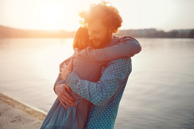 Foto casal feliz, abraçando-se em um dia ensolarado perto do lago