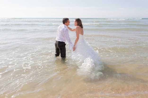 Casal feliz acabou de se casar relaxando na praia deitado no oceano