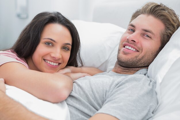 Casal feliz acordando e olhando para câmera