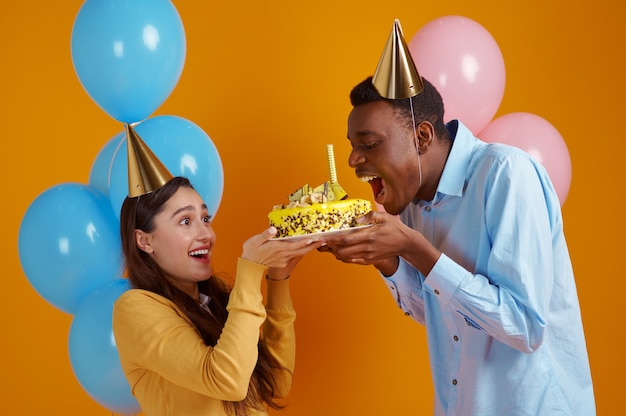 Casal feliz amor no caps segurando um bolo de aniversário com fogos de artifício. Linda festa em família, evento ou festa de aniversário, decoração de balões