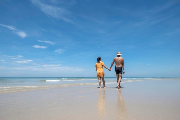 Foto casal feliz apaixonado brincando na praia em corrida ensolarada e espirrando nas ondas viajam o estilo de vida de férias