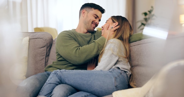 Casal feliz apaixonado e juntos no sofá na sala de estar para contato visual confiança ou ligação homem mulher e casado com abraço para abraço em cuidado romântico ou conforto em conexão em lua-de-mel em casa