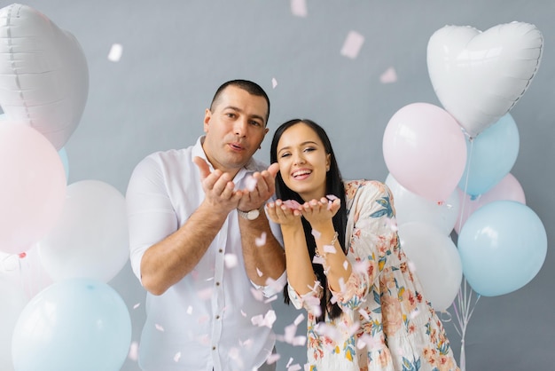 Casal feliz apaixonado soprando confete em homenagem ao seu amor no fundo dos balões