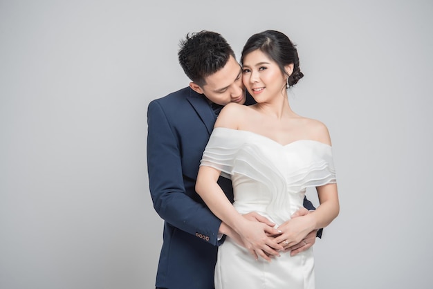 Casal feliz asiático, noivo e noiva com vestido de noiva em fundo branco