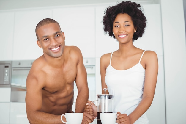 Casal feliz bebendo café na cozinha em casa