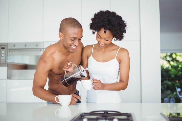 Casal feliz bebendo café na cozinha em casa