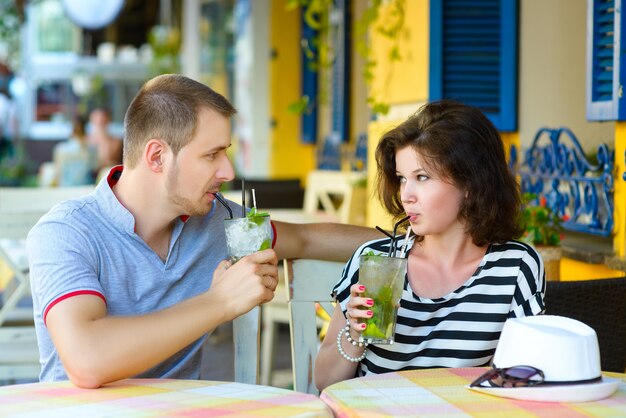 Casal feliz bebendo limonada ou mojito em um café do lado de fora.