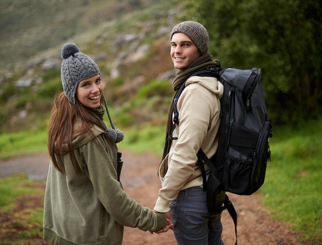 Casal feliz caminhando pelas montanhas e de mãos dadas para aventuras ao ar livre viagem de viagem e retrato Jovem homem e mulher com amor data ecológica e caminhada ou caminhada em mochila para o inverno