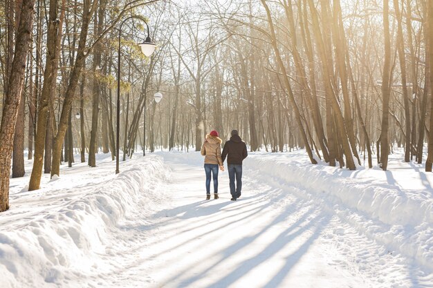 Casal feliz caminhando por um bosque nevado no inverno.