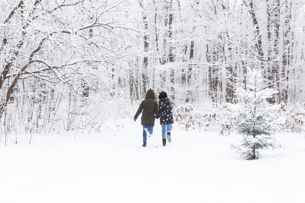 Casal feliz caminhando por um bosque nevado no inverno.