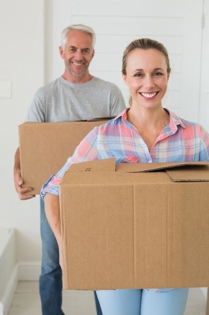 Casal feliz carregando caixas de papelão em movimento