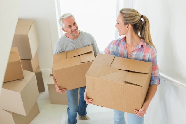 Casal feliz carregando caixas de papelão em movimento