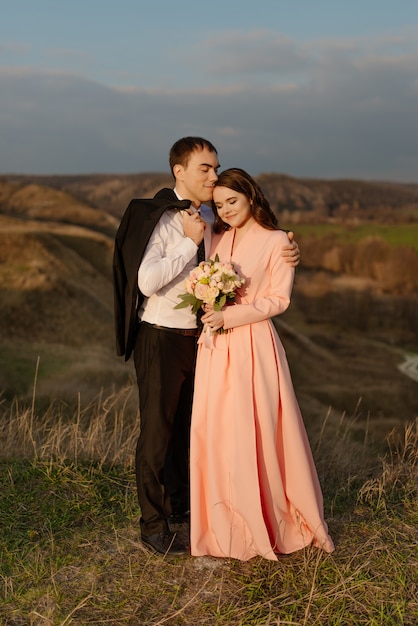 Casal feliz casamento admira a bela paisagem ao pôr do sol.