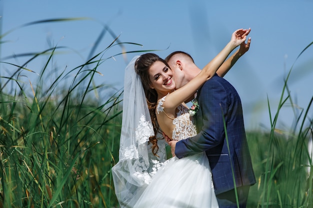 Casal feliz casamento andando na ponte de madeira. emocional noiva e o noivo abraçando suavemente ao ar livre.