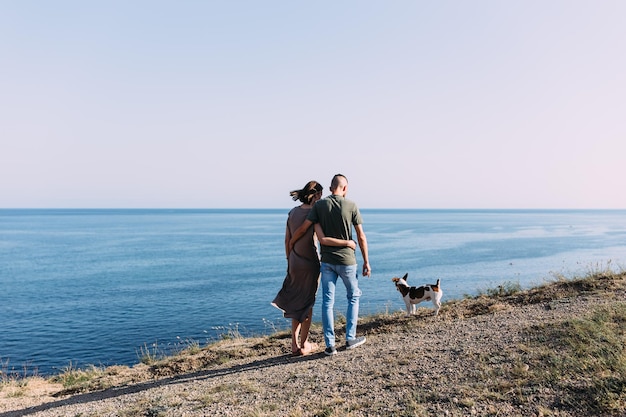 Casal feliz com animal de estimação favorito, jovem e mulher, andou perto do mar