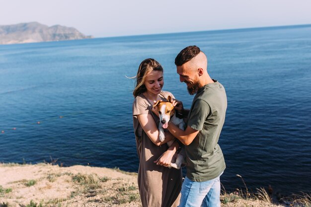 Casal feliz com animal de estimação favorito, jovem e mulher, andou perto do mar