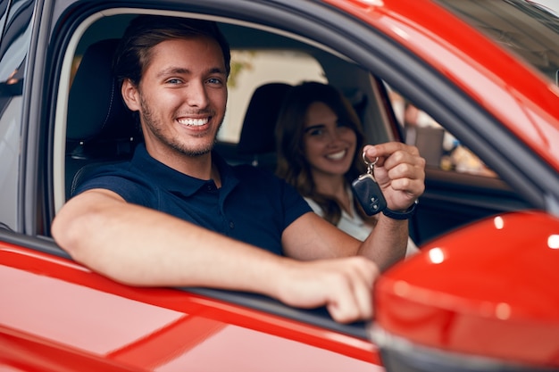 Casal feliz com as chaves no carro