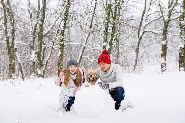 Casal feliz com cocker spaniel fazendo boneco de neve