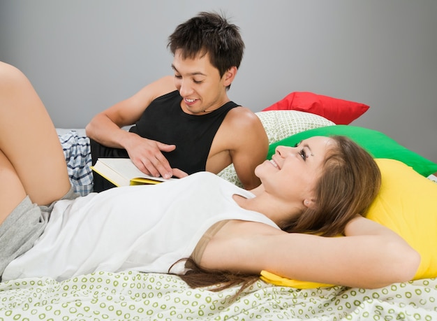 Casal feliz com livro na cama