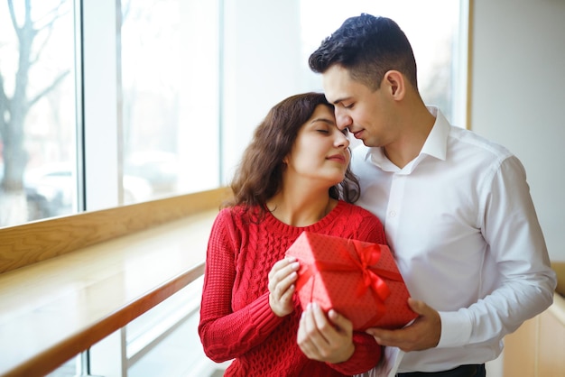 Casal feliz com presente abraçando Caixa de presente vermelha nas mãos de um casal apaixonado Dia dos Namorados