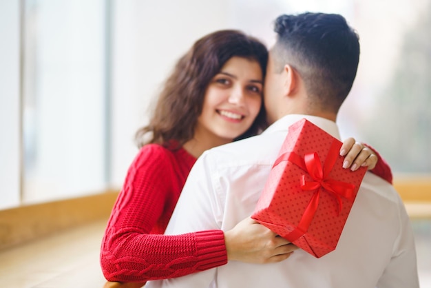 Casal feliz com presente abraçando caixa de presente vermelha nas mãos de um casal apaixonado dia dos namorados