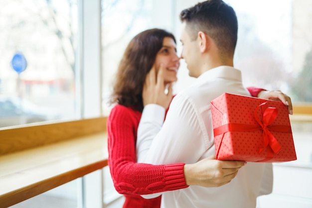 Casal feliz com presente abraçando Caixa de presente vermelha nas mãos de um casal apaixonado Dia dos Namorados