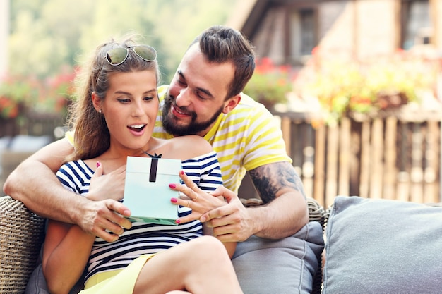 Casal feliz com presente sentado ao ar livre