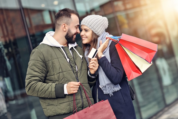 casal feliz com sacolas de compras depois de fazer compras na cidade, sorrindo e se abraçando