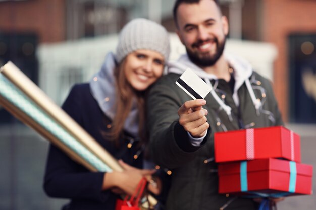 Casal feliz com sacolas de compras depois de fazer compras na cidade, sorrindo e se abraçando