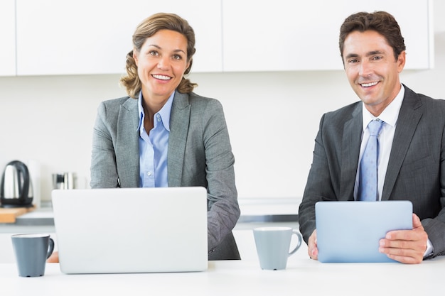 Casal feliz com tablet e laptop