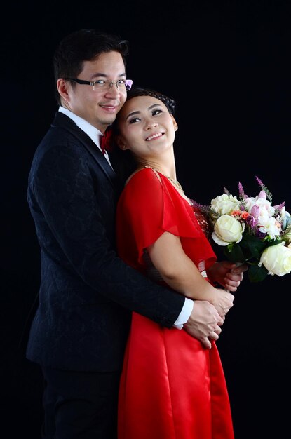 Foto casal feliz com um buquê de pé em fundo preto