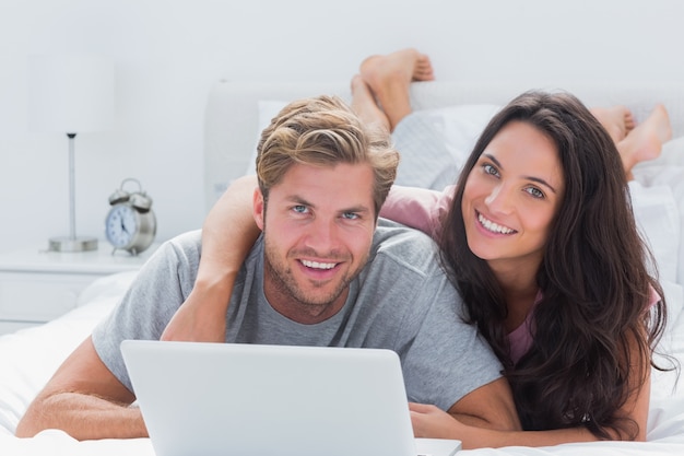 Casal feliz com um laptop na cama