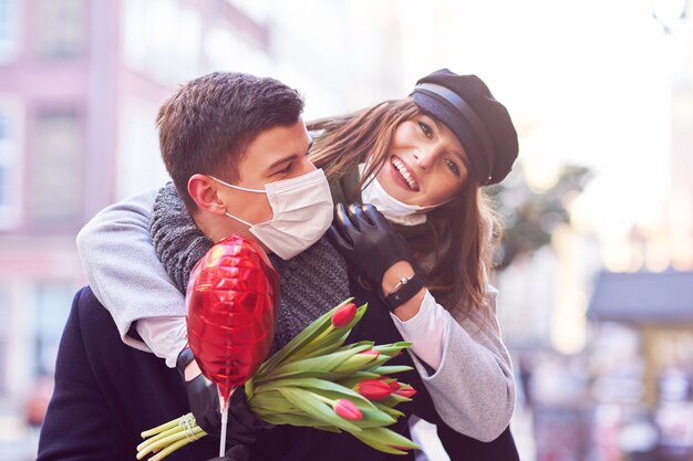 Casal feliz comemorando o Dia dos Namorados com máscaras durante a pandemia covid-19 na cidade