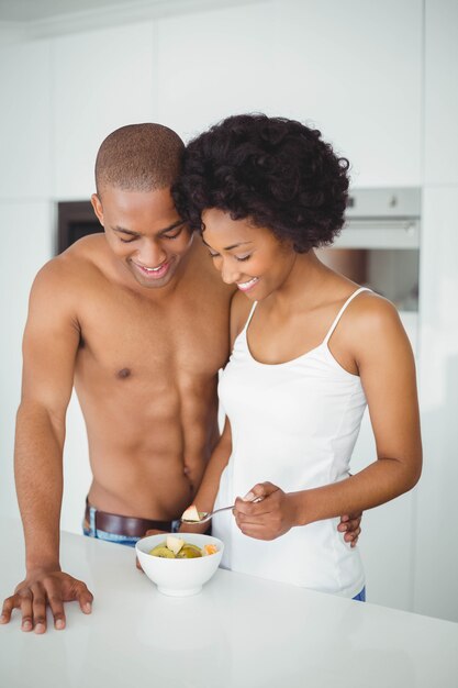 Casal feliz comendo frutas juntos na cozinha em casa