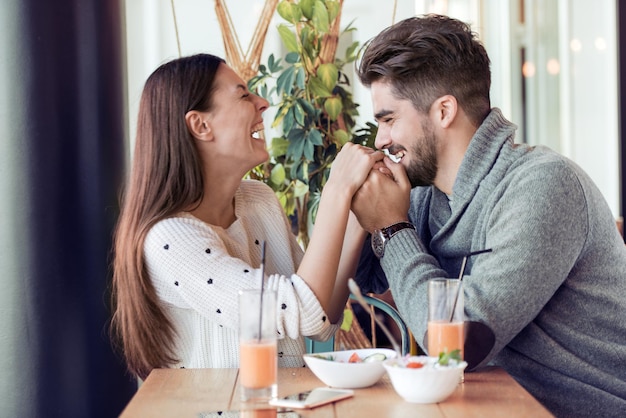 Casal feliz comendo salada no almoço no café