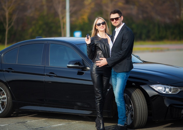 Casal feliz compra novo carro preto moderno