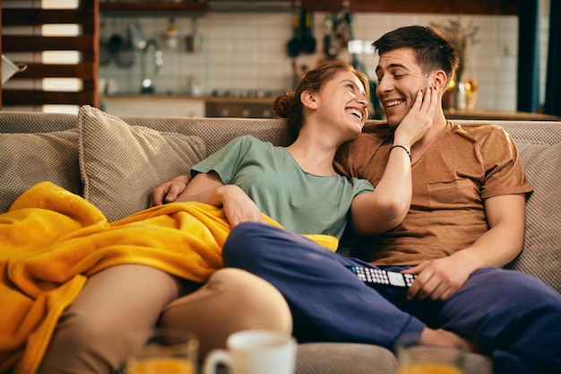 Casal feliz conversando enquanto relaxa no sofá em casa