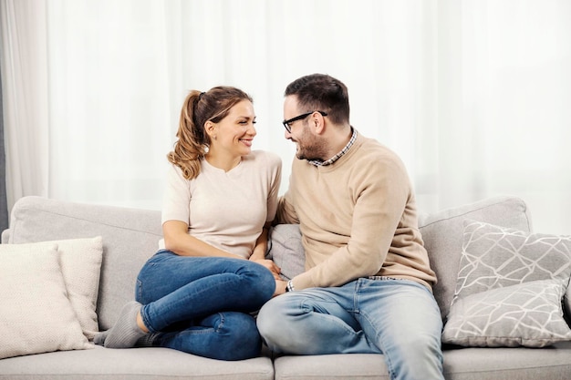 Casal feliz conversando no sofá em seu confortável apartamento