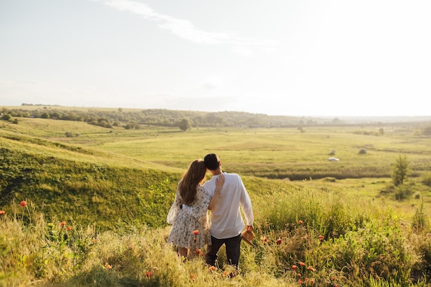 Casal feliz correndo e flertando entre a grama em um campo de papoulas verdes na primavera