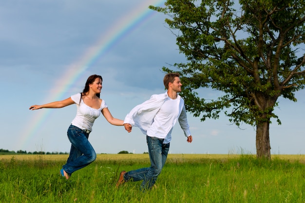 Casal feliz correndo em um prado