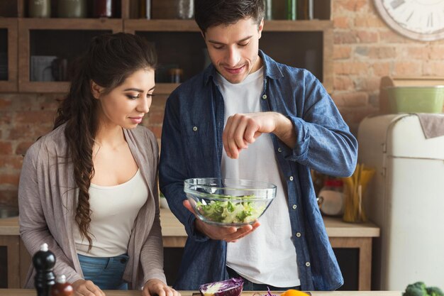 Casal feliz cozinhando alimentos saudáveis juntos na cozinha do sótão em casa. Preparando salada de vegetais, copie o espaço