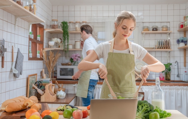 Casal feliz cozinhar salada no café da manhã na cozinha de casa