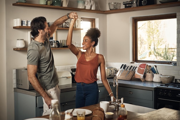 Foto casal feliz dança e se diverte se unindo na cozinha para romance, amor ou férias juntos em casa homem e mulher inter-raciais dançando de felicidade para relacionamento romântico ou aproveitando o fim de semana em casa