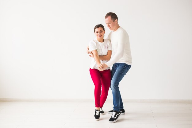 Casal feliz dançando kizomba vs bachata ou salsa ou zouk em fundo claro