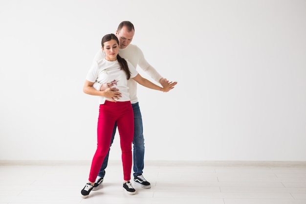 Casal feliz dançando kizomba vs bachata ou salsa ou zouk em fundo claro