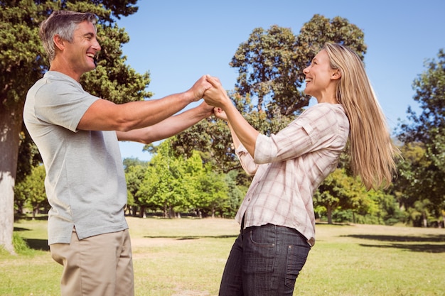 Casal feliz dançando no parque