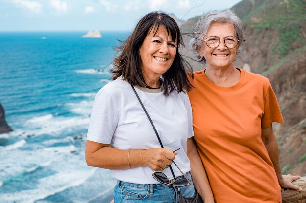 Casal feliz de amigas idosas juntas no mar olhando para a câmera desfrutando de um belo destino de viagem estilo de vida livre e conceito de aposentadoria